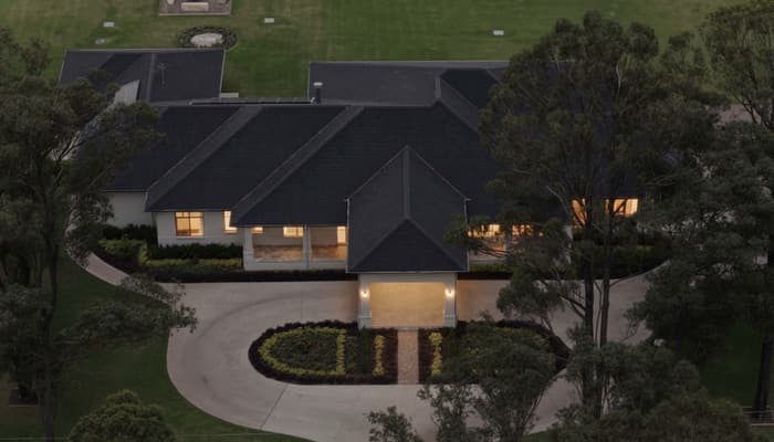 Front facade at dusk with entry portico lit and gates open
